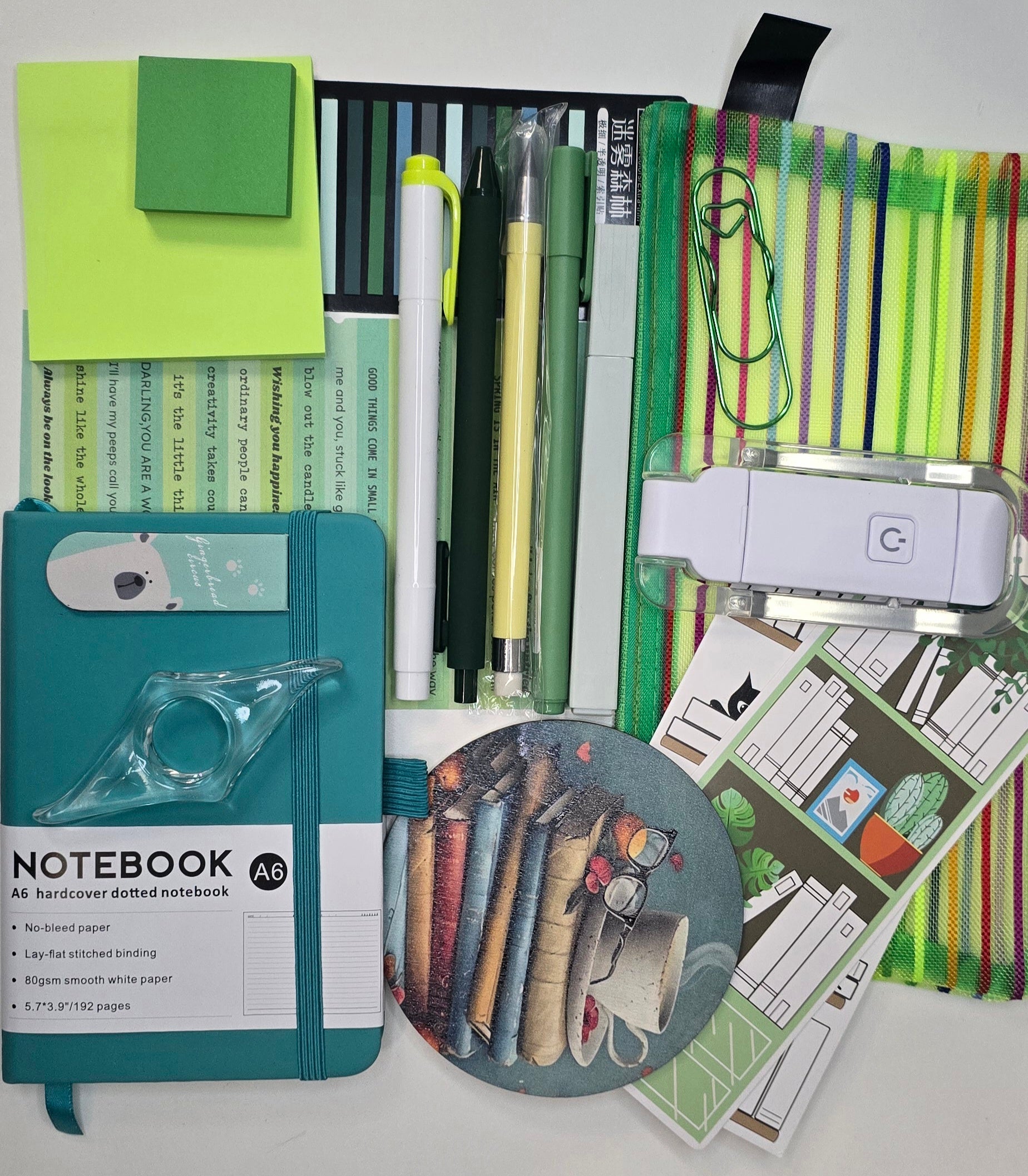 Collection of stationery items including a notebook, pens, and a printer on a white background