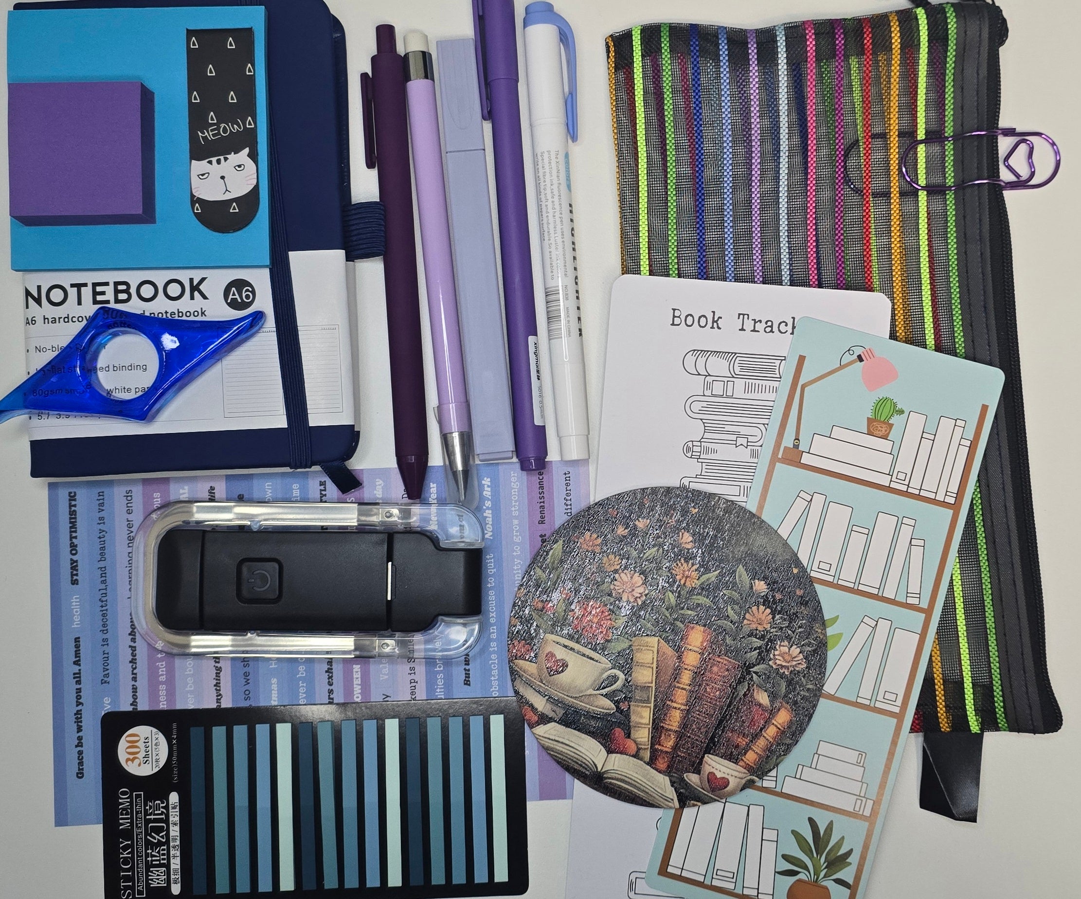 Collection of stationery items including pens, a notebook, and decorative stickers on a white background.